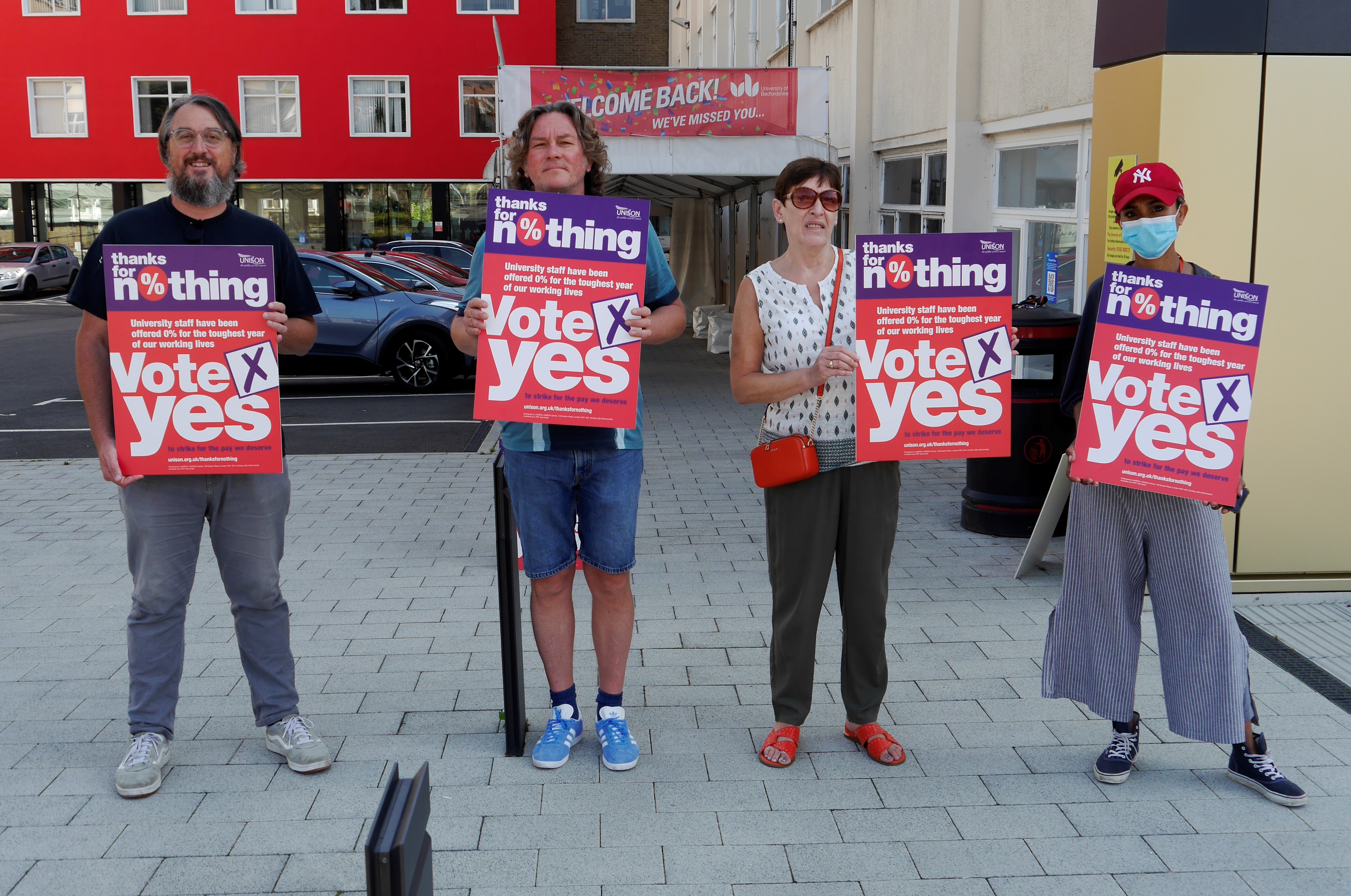 Four people hold up signs reading 'Vote Yes'
