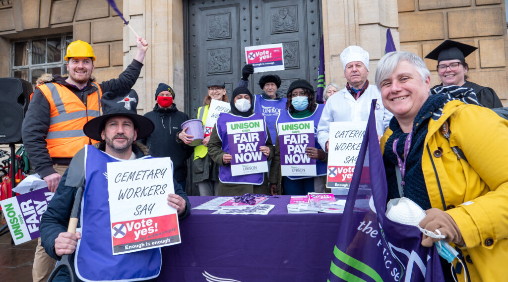 A group of protesters pose for a photo while calling for fair pay