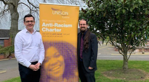 Stephen Collman and Peter Passingham stand by a sign for the Anti-Racism Charter