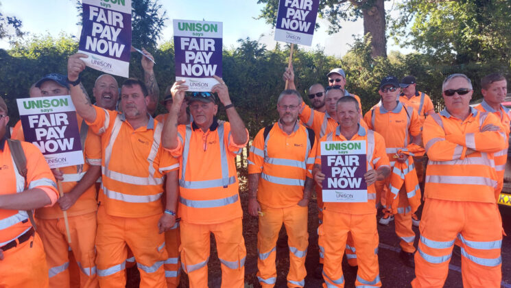 Refuse workers hold signs reading: 'Fair pay now'