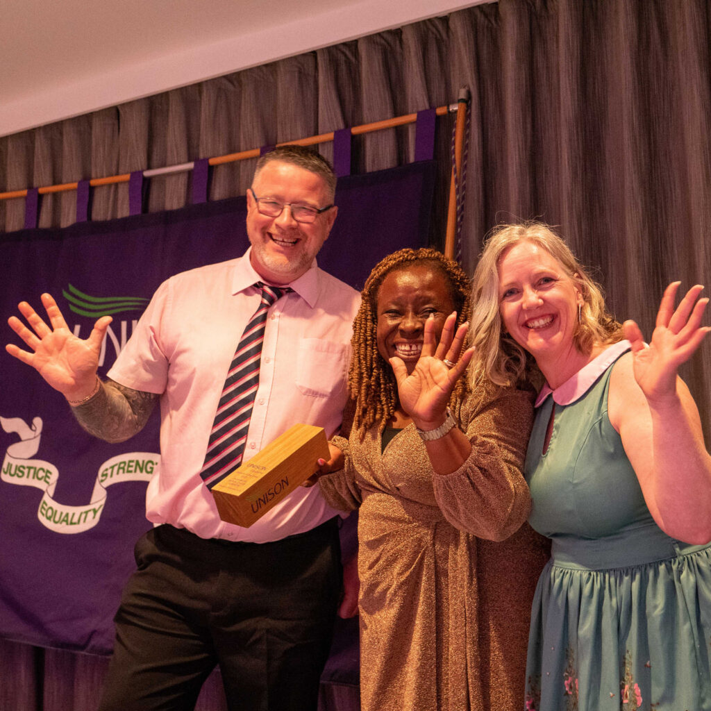 Neil and Gwenda from Suffolk County pick up their award from Becky, celebrating with jazz hands