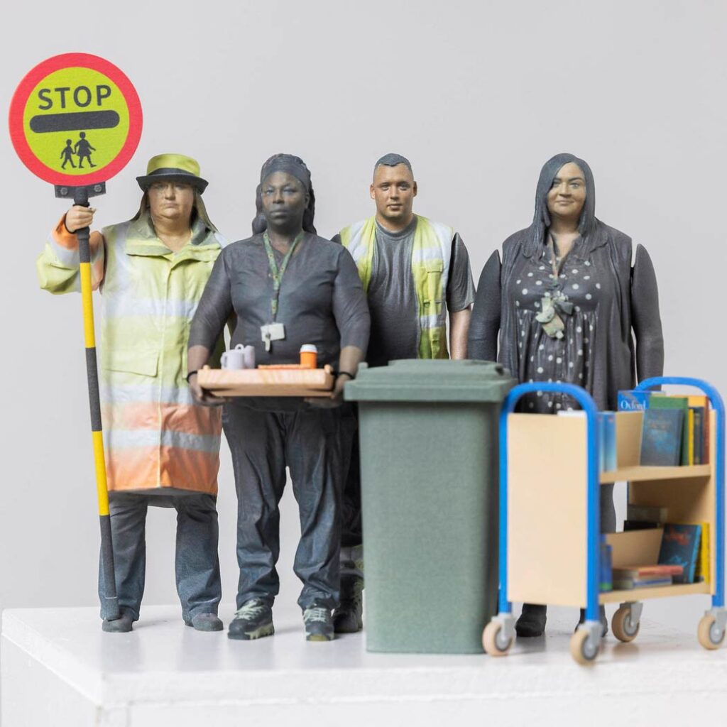 The four action figures — a a lollipop lady holding her sign, a care worker holding a tray, a refuse worker with a wheelie bin and a librarian with book trolly.