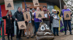 People hold signs bemoaning plans to shut down public toilets