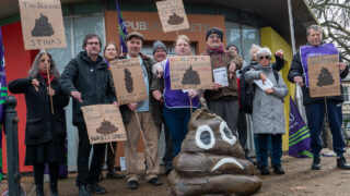 People hold signs bemoaning plans to shut down public toilets