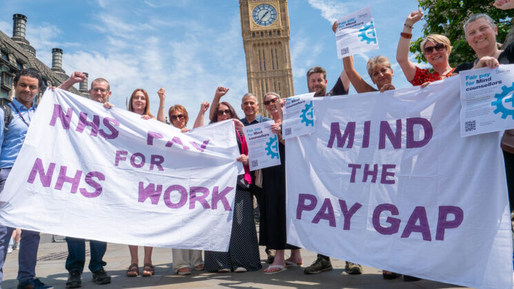 Mind counsellors stand outside the Houses of Parliament with banners reading 'NHS pay for NHS work' and 'Mind the pay gap'