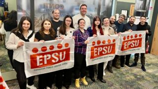 Young workers pose with EPSU flags